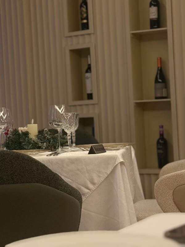A set dinner table, wine on the shelves behind