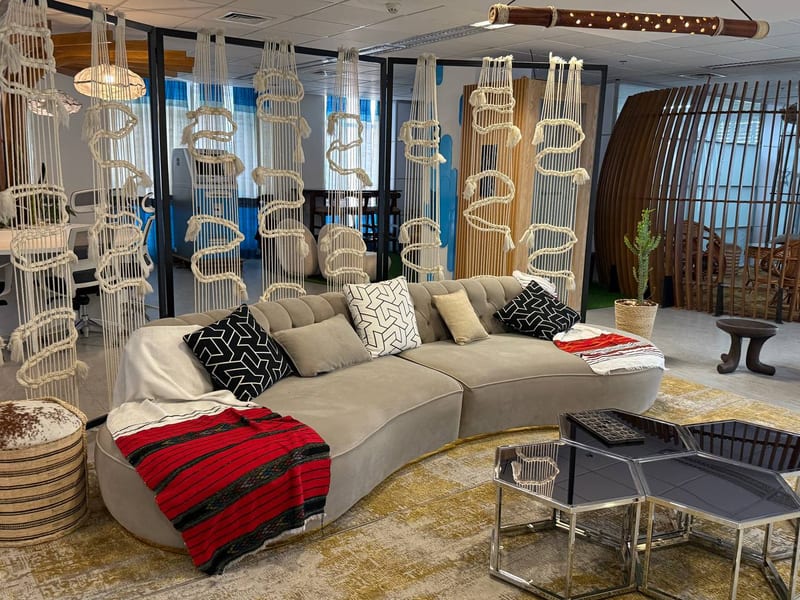 A lounge with a curved sofa, a red blanket and a small wooden stool