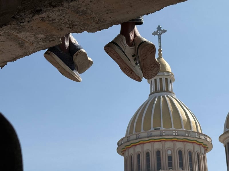 Our feet over a ledge above a church dome and its cross