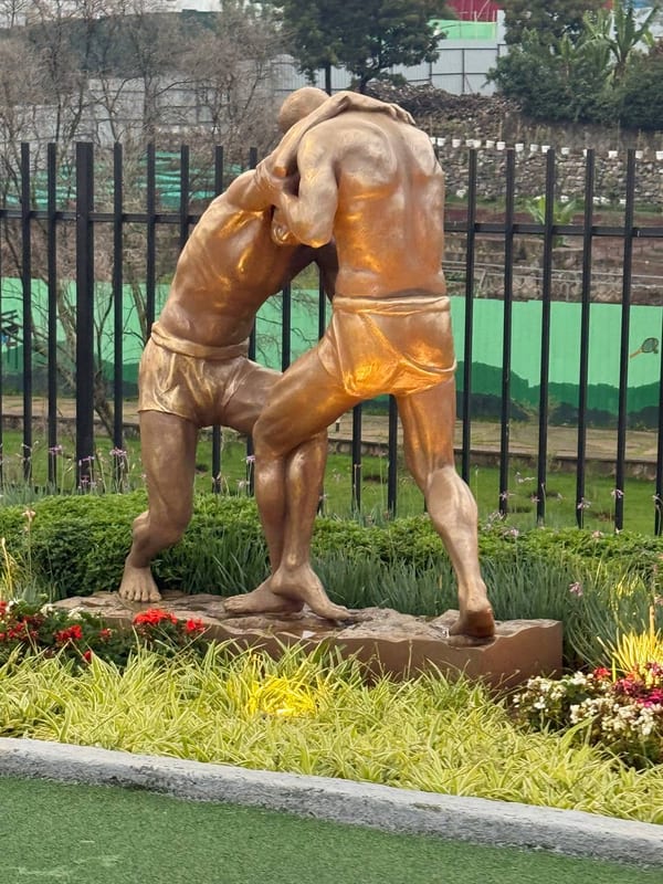 A bronze statue of two wrestlers in a park