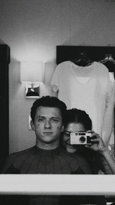 Tom Holland and Zendaya taking a mirror photo with an instant camera