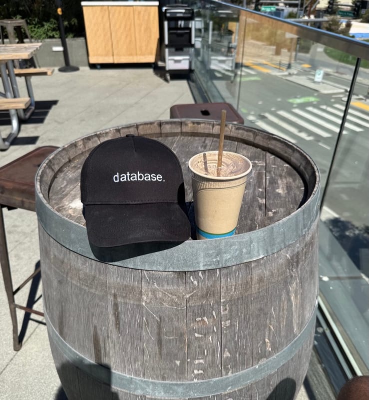 A "database." cap and a coffee on a barrel table