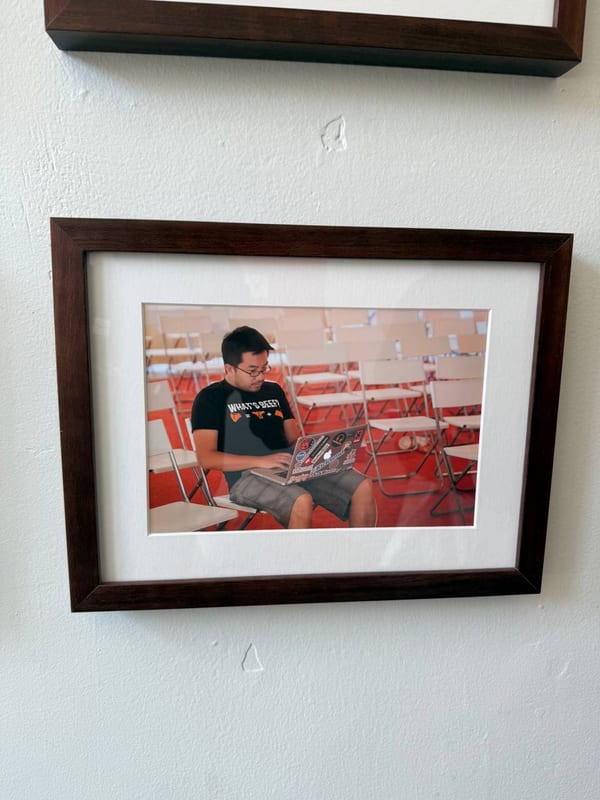 A framed photo on a wall of someone coding in a lecture hall
