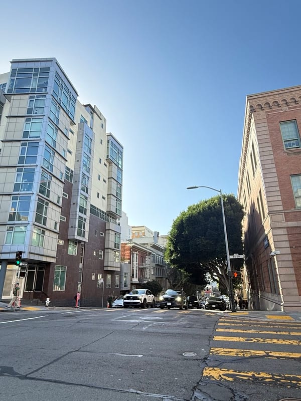 A street corner of glassy apartment blocks under a clear sky