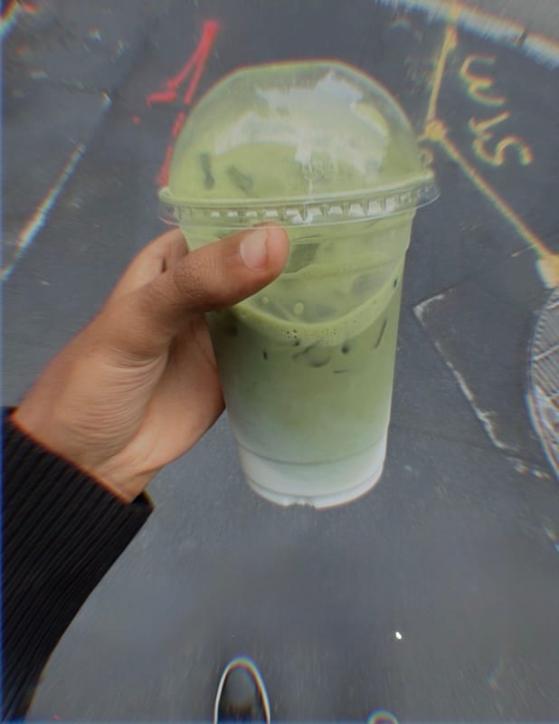 An iced matcha in my hand over a painted street