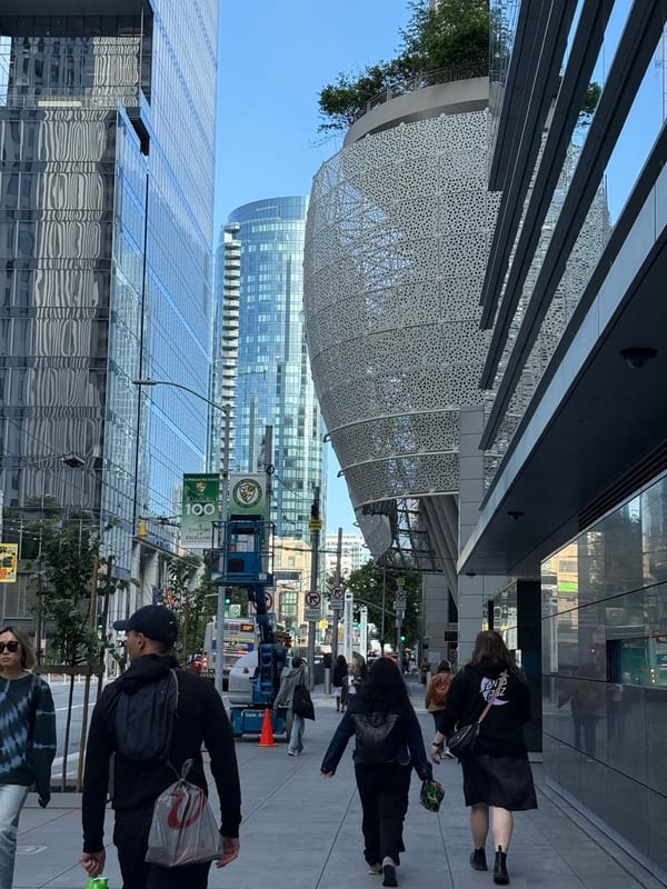 People walking past glass towers and a curved lattice building