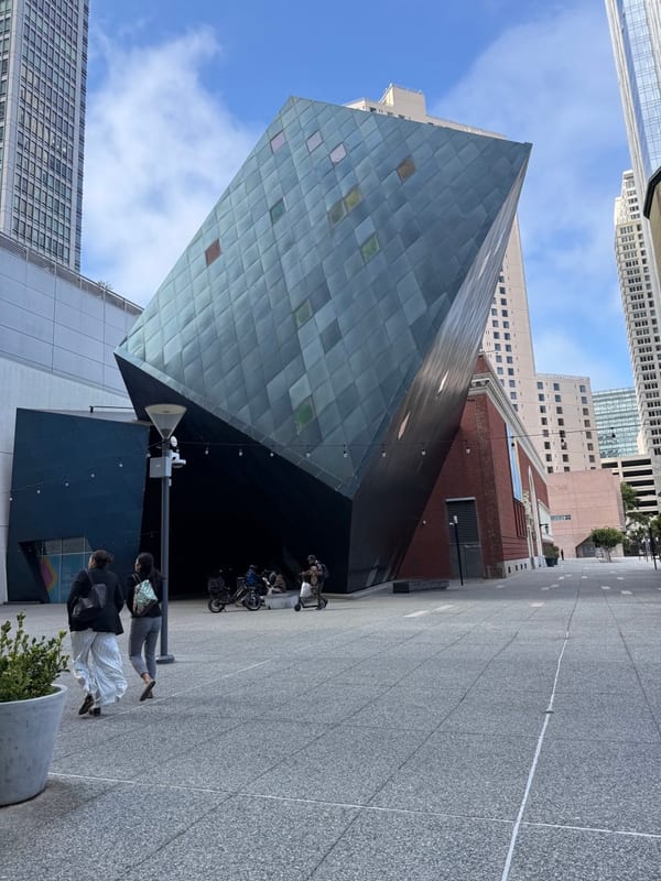 A tilted blue cube of a museum over a wide plaza
