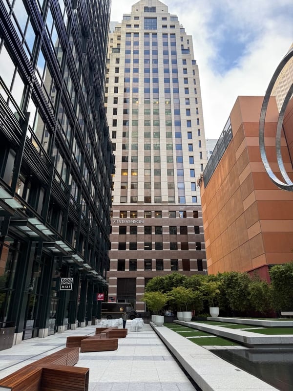 A tall tower at the end of a quiet walkway, an orange building beside it