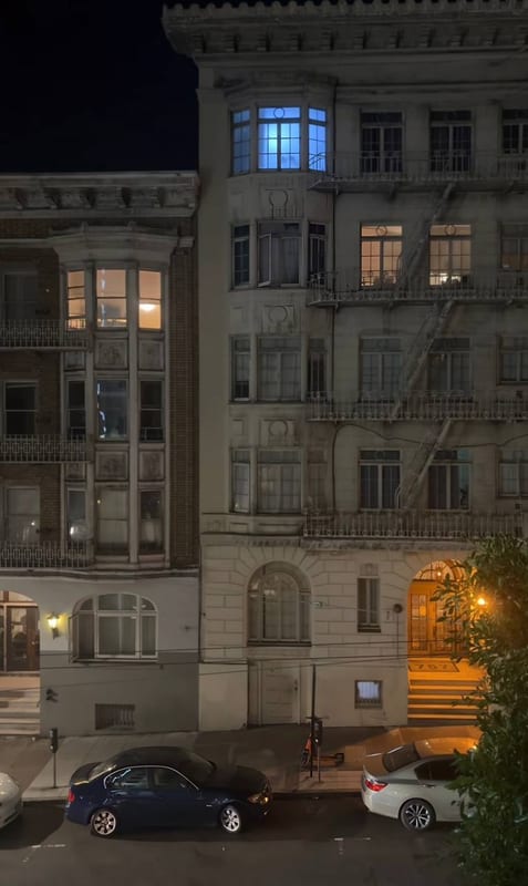 An old building at night, one window lit blue