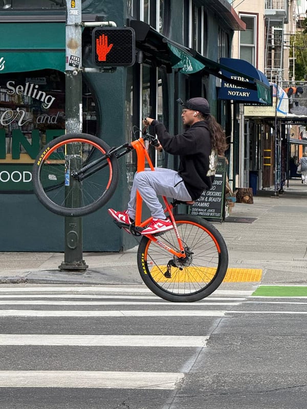 A rider pulling a wheelie across a crosswalk