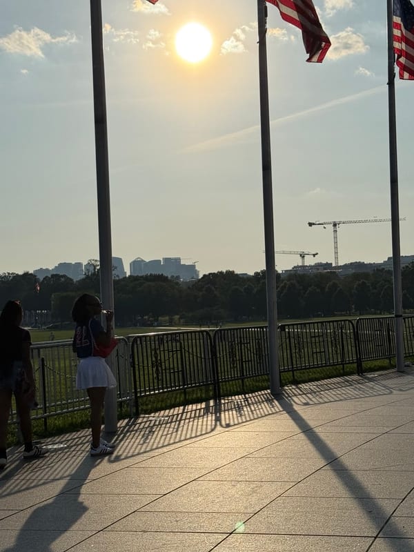 Flags against the low sun, people at the railing
