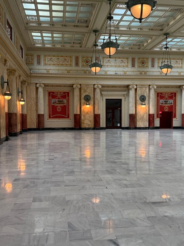 A marble hall with hanging lamps under a glass ceiling